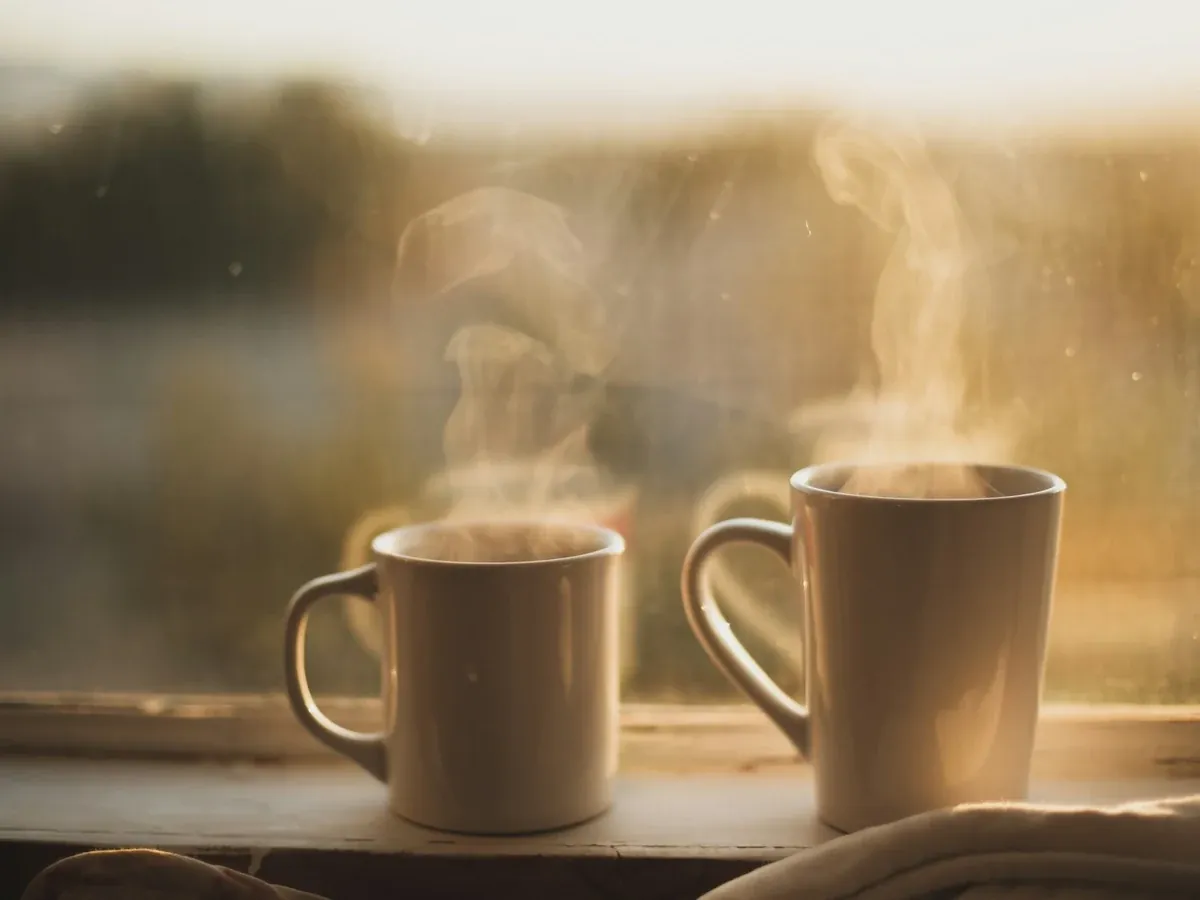 Two steaming mugs on a windowsill — a pause from the table